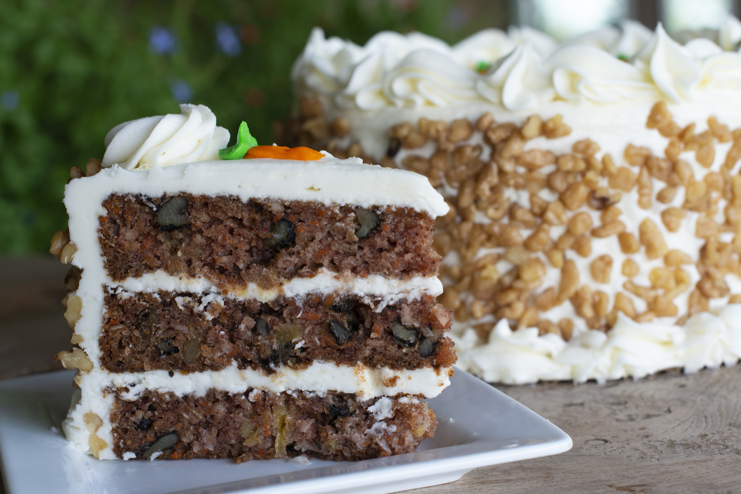Slice of Carrot Cake on white plate with full cake behind it